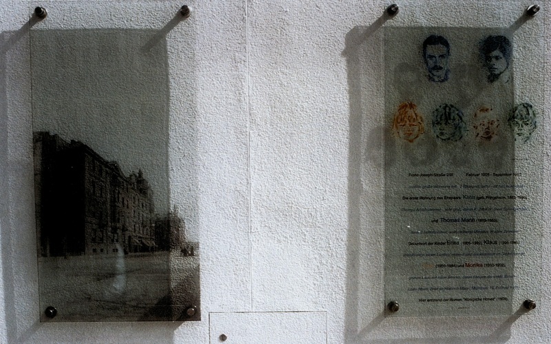 Gedenktafeln an die erste Wohnung der Familie Mann in der Franz-Joseph-Straße 2, 2023 Die rechte Tafel zeigt mit Glasmalereien von Joachim Jung Porträts von Thomas, Katia (oben), Golo, Erika, Monika und Klaus Mann (unten). Der Text (biografische Daten: Dirk Heißerer, Textmontage: Joachim Jung) verschränkt die Lebensdaten der ehemals hier lebenden Familienmitglieder mit einer zeitgenössischen Schilderung von Julia Mann, der Mutter Thomas Manns. Auf Initiative des Thomas-Mann-Forums München e. V. wurden die beiden Glastafeln im Juli 2000 in Zusammenarbeit mit der Hypo-Kulturstiftung an der Franz-Joseph-Straße 2, damals Gästehaus der Bank, montiert und eingeweiht. Linke Tafel: Siebdruck auf Glas nach der Fotografie von Georg Pettendorfer | Rechte Tafel: Glasmalerei von Joachim Jung. Erstellt von: Joachim Jung